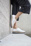 Womanâs legs in casual Shoes at wall