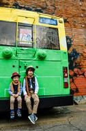 boys on the bumper of a green trolley