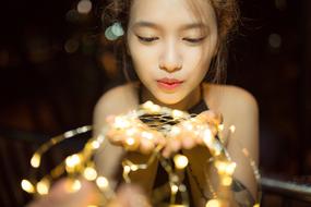 Asian woman holding garland lights