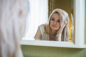 serious Blonde Girl looking at mirror