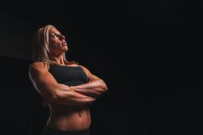 adult woman with muscular body at darkness