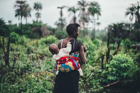 african woman with baby on back in wilderness