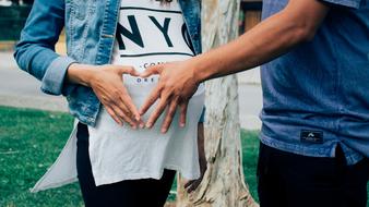 a man holding a pregnant girl by the belly