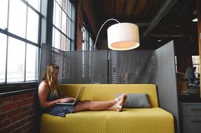 girl with laptop on sofa in office