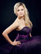 Beautiful, blonde girl, with the make-up, in purple black dress, posing at black background