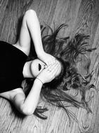 black and white, a girl lies on the floor with her eyes closed