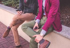 two young stylish men sitting in a park