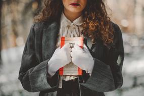 woman in white gloves with a book in her hands