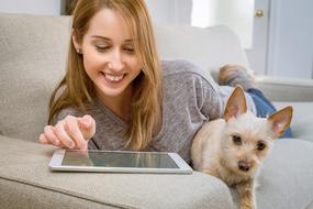 girl with Tablet and doggy resting on sofa