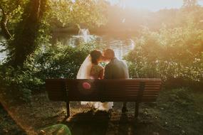 newlyweds on a park bench near the pond