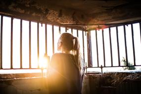 Woman looking at sun through grate