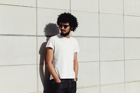 Guy in white t-shirt stands at wall