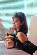Beautiful Asian girl with the glasses, eating popcorn