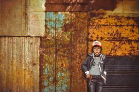 schoolboy in fashionable clothes posing against a rusty wall