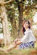 girl sitting on the ground near the trees