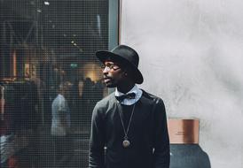 young dark skin Man in black outfit at wall
