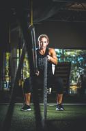 young woman doing exercise with rope in gym