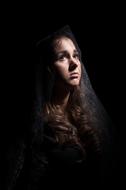 sad young Woman with black veil on Hair at darkness