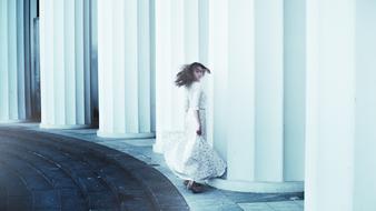 girl in a white dress among huge columns