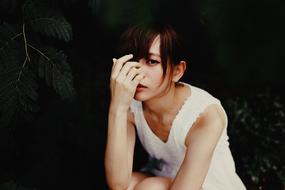 depressed woman in white dress sits at darkness