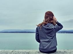 Girl in blue hoodie Looking at sea