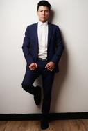 young man in suit leaning on wall