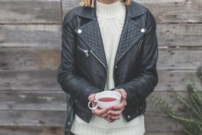 young girl with drink in cup at wooden wall