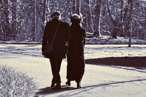 monochrome photo of an elderly couple walking in the park among trees