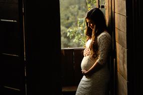 pregnant woman in white posing near the window