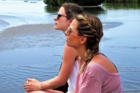 two young girls sitting at water