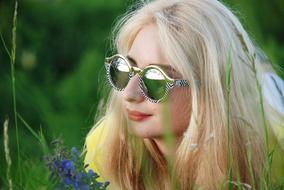 Girl in stylish glasses laying on grass