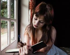 thoughtful sexy girl Writing Diary at window