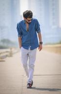 photo of a young man in a denim shirt walking along the road