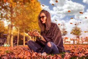 photo of a beautiful girl sitting on autumn foliage