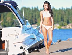 girl in a white bikini on the pier near the boat