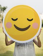 girl holding a smiley face in her hands
