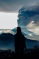 silhouette of a girl on the background of a volcano at dusk