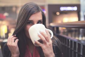 young girl Drinking from white Mug
