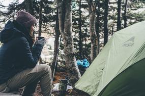 girl sitting near the tent in the forest