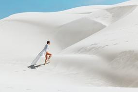 Girl in white clothing walking on beautiful white sand on landscape
