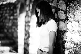 black and white, brunette stands against the wall