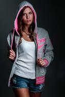 Posing woman in pink and gray sweatshirt, at dark background