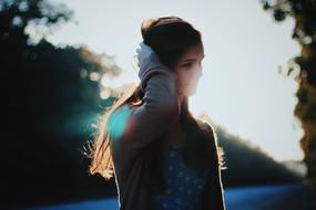 Posing girl among the trees at bright bokeh sunrise