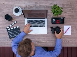 Filmmaker, working with the laptop, camera and other devices, on the desk, at the workplace