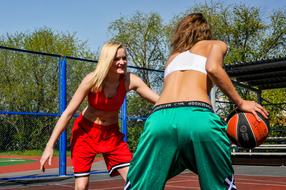Girls, playing basketball on the court, in the colorful park