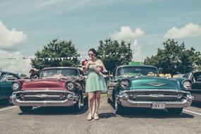 Woman in glasses, with the baby, among the colorful and beautiful, vintage oldtimer cars
