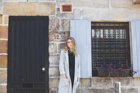 Beautiful, young, blonde woman, near the house, with the door and window