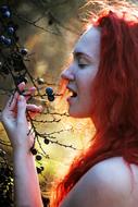 red-haired beauty near a bush with berries in nature