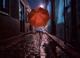 Woman with the orange umbrella, working on the wet street