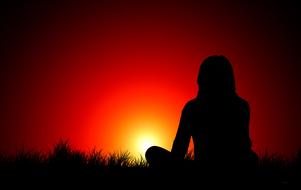 woman in meditation silhouette at the background of red sunset